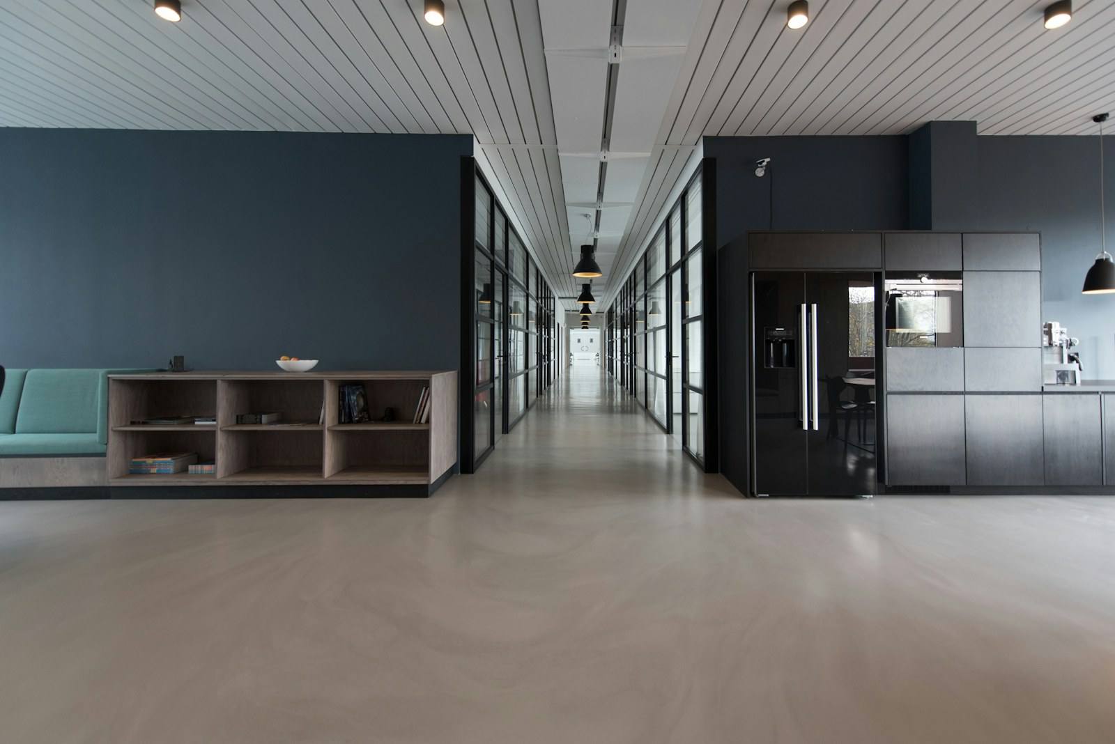 A modern office corridor with glass-walled meeting rooms